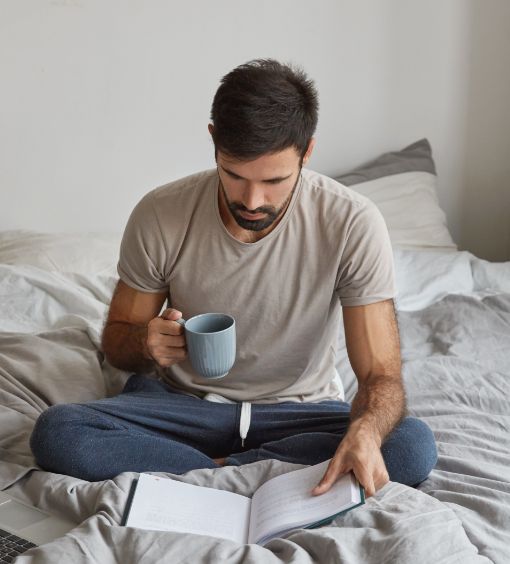image-young-caucasian-man-has-morning-coffee-sits-crossed-legs-bed